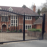 A black gate with two pillars that is fully automated