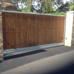 An automated, square wooden gate with two surrounding pillars