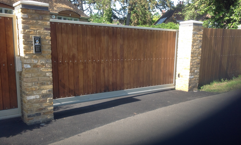 An automated, square wooden gate with two surrounding pillars
