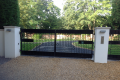 A large black metal gate with two white pillars