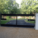 A large black metal gate with two white pillars