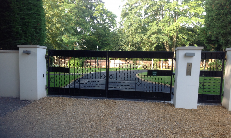 A large black metal gate with two white pillars