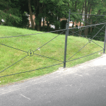 A metal gated railing with a green lawn background