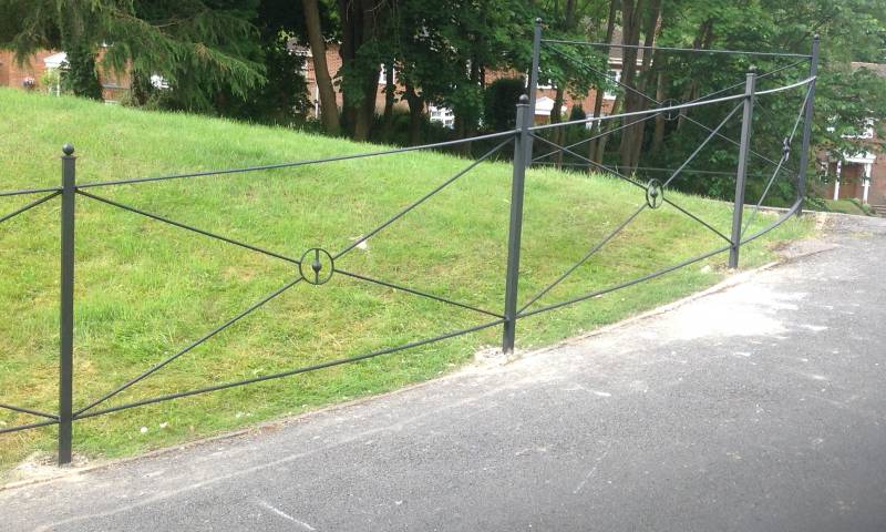 A metal gated railing with a green lawn background